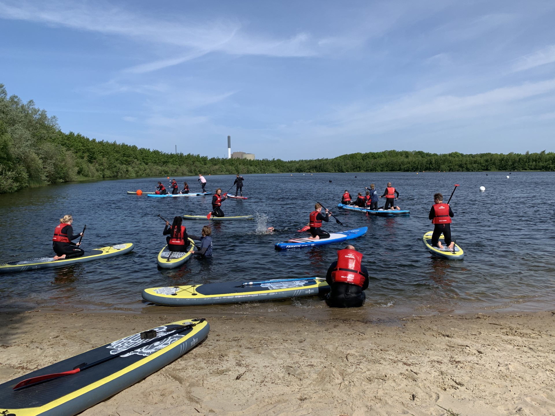 Unge med redningsveste på SUP-boards ved en sø.