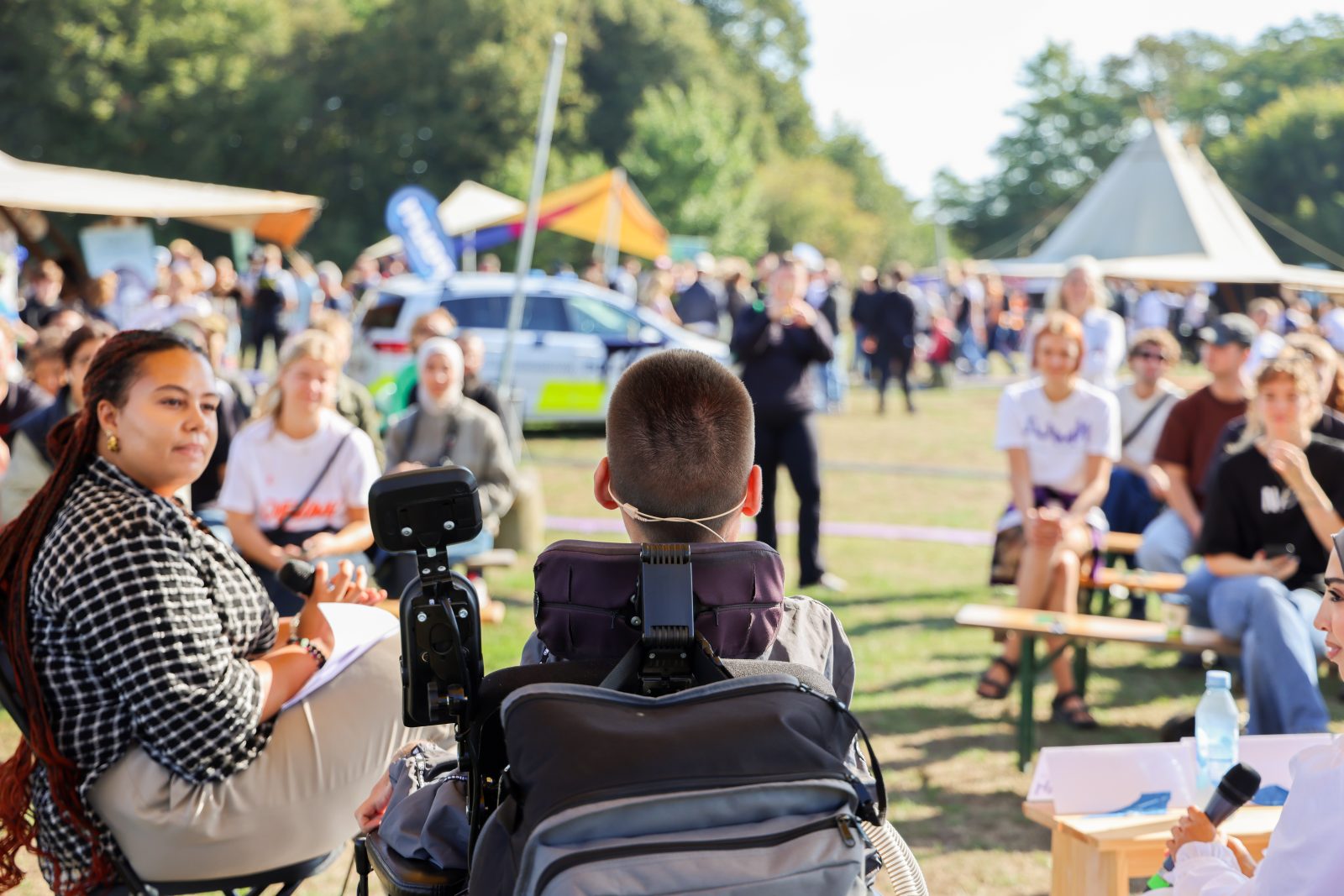 Ung person i kørestol, der holder oplæg udendørs.
