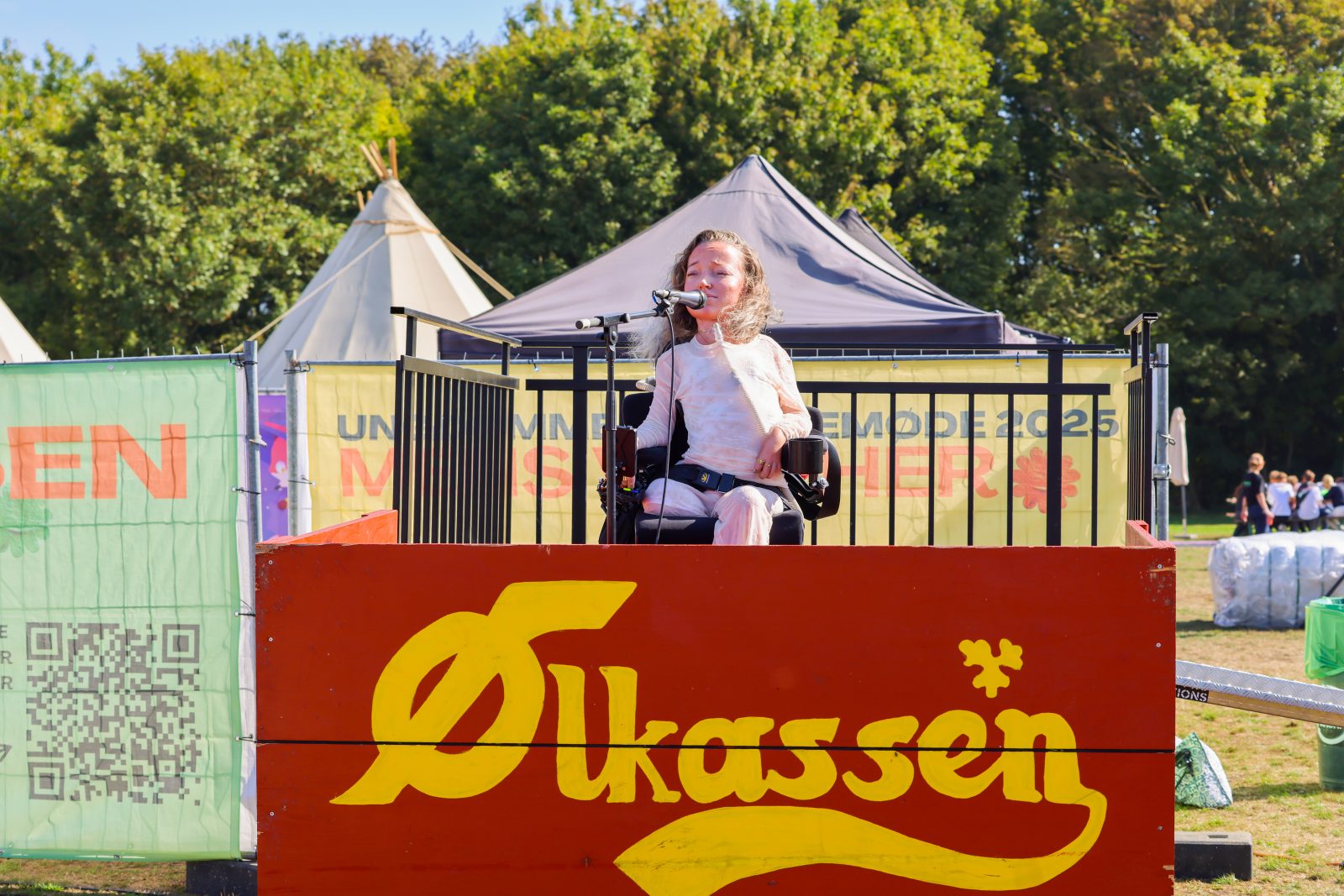 Ung kvinde i kørestol holder tale. Hun taler ind i en mikrofon