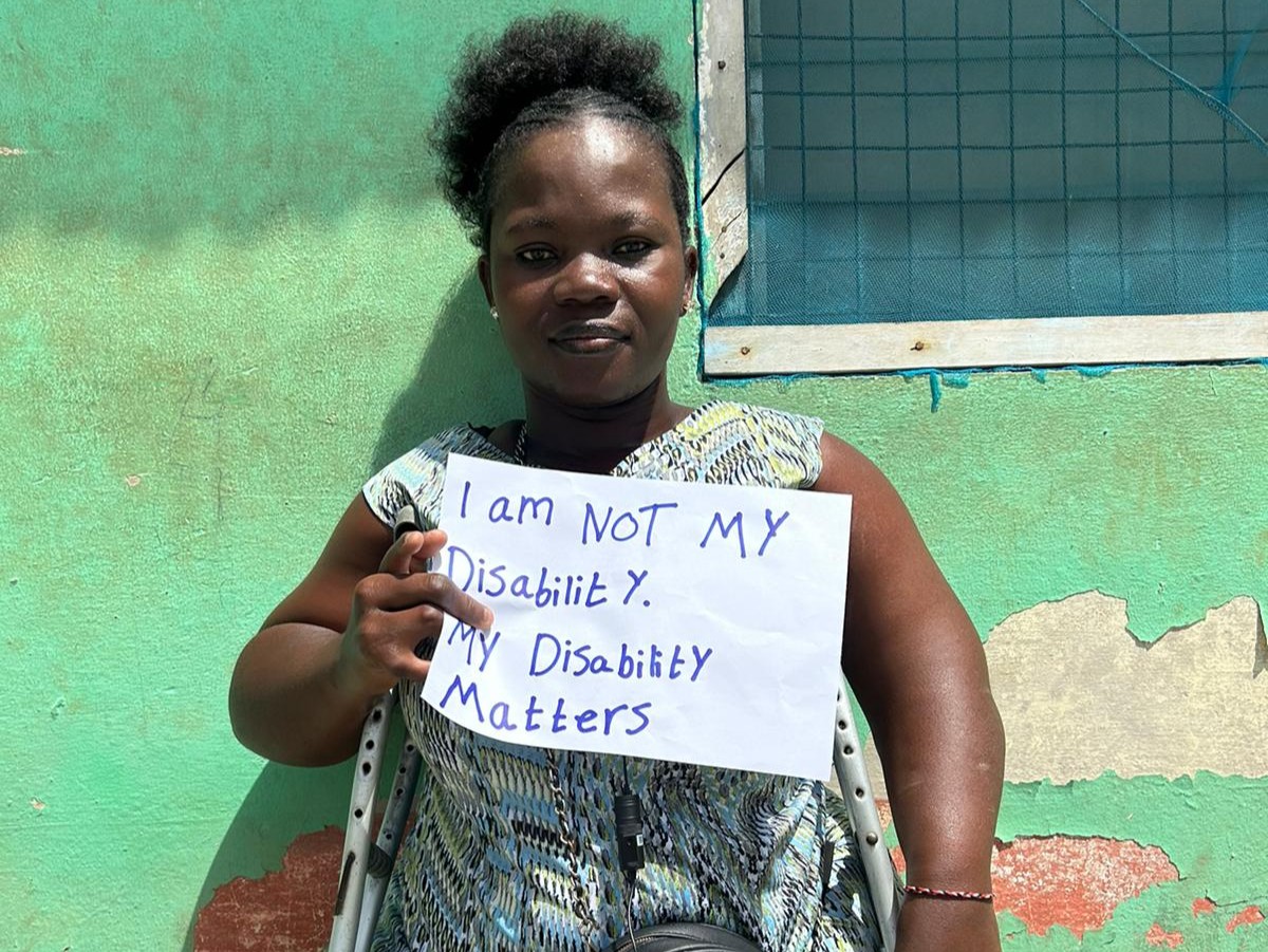 Person står med skilt, hvor der står I am not my disability. My disability matters.