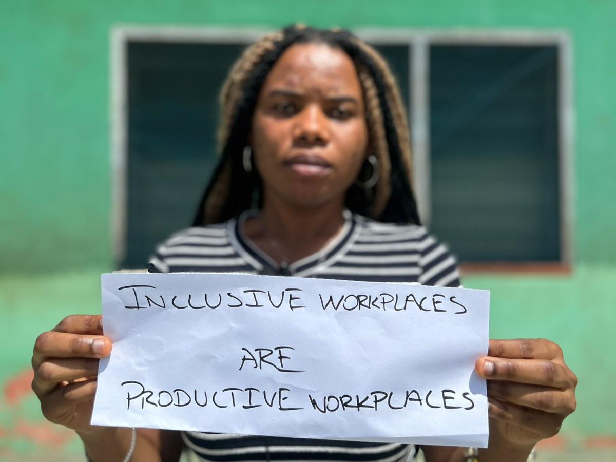Person står med et skilt, hvor der står Inclusive workplaces are productive workplaces
