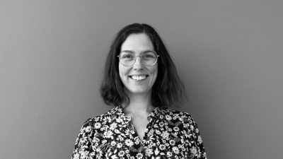 Alice smilende kvinde i 40'erne med mørkt hår og briller.